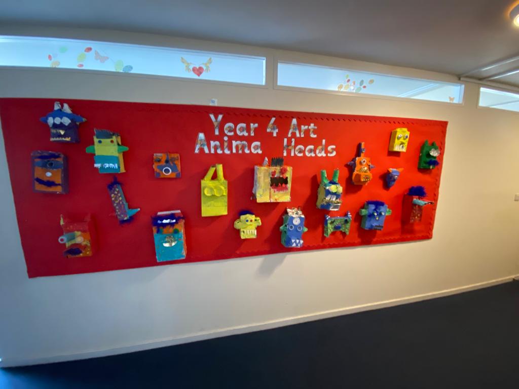 Display of 3D creature heads school art paper mache project